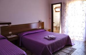 弗卢米尼马焦雷Agriturismo Perdaba的一间卧室配有两张紫色床单