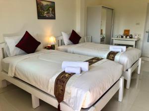 讪巴东Naraya Homestay的一间卧室配有两张带白色床单和红色枕头的床。