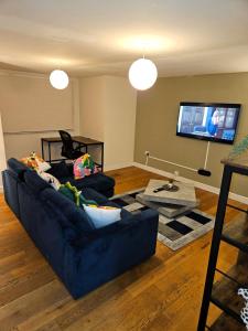 伦敦London O2 ARENA COOL BREEZE HOUSE的客厅配有蓝色的沙发和平面电视。
