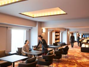 大阪大阪丽嘉皇家酒店的两人站在带桌椅的房间