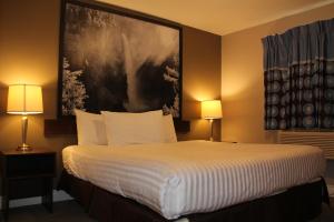 坎卢普斯Super 8 by Wyndham Kamloops On The Hill的酒店客房设有一张壁挂着大画的床铺。