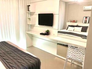 邦比尼亚斯Muito confortável, vista do mar, todo climatizado的一间卧室配有一张桌子、一台电视和一张床