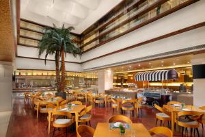 滨海新区天津滨海皇冠假日酒店的一间设有木桌和椅子的餐厅,并种植了棕榈树