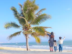 汕尾汕尾保利希尔顿逸林酒店的一家站在海滩上棕榈树旁的家庭