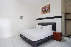 库塔巴厘岛城市花园德维帕酒店的卧室配有一张白色床,墙上挂着一幅画