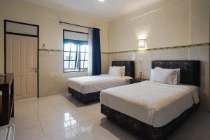 库塔巴厘岛城市花园德维帕酒店的酒店客房设有两张床和窗户。