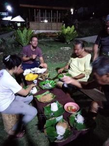BatuanROCA'S HOMESTAY Backpackers Chalet Bohol的一群人坐在桌子旁吃着食物