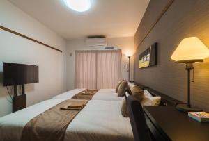 那霸KINTARO Hotel Okinawa Naha的酒店客房设有一张大床和一张书桌。