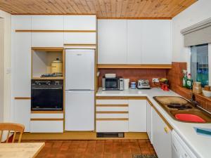阿利士Smiddy Cottage的厨房配有白色橱柜和黑色冰箱。