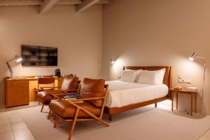 佩纳菲耶尔DOURWIN - Riverside Suites - Adults Only的一间卧室配有一张床、一把椅子和一张书桌