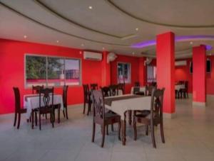 西里古里Mountain Green Club and Resort的一间拥有红色墙壁和桌椅的用餐室