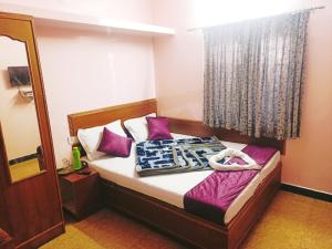 乌提SNR Cottage & Rooms的一间卧室配有一张带紫色枕头和镜子的床