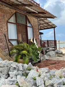 瓜拉丁加奴Rumahbatu beach cottage的前面有植物的砖房