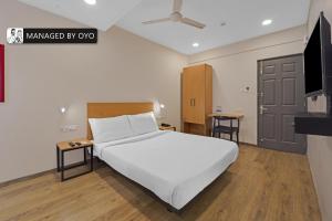 钦奈Super Townhouse OMR Laxmi Nagar的卧室配有白色的床和平面电视。