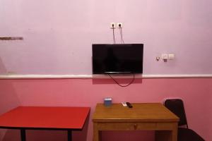 马格朗OYO 93660 New Family Hotel Syariah的一间设有桌子的房间和一台粉红色墙壁上的电视
