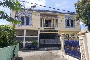 肯达利OYO 93650 Pondok Baruga 777的一座带门和蓝色围栏的房子