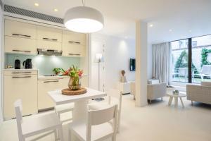 布鲁塞尔丽晶B公寓式酒店的厨房以及带桌椅的起居室。