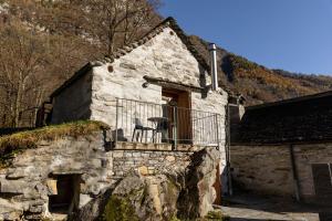 SonognoVerzasca Lodge Elma的石头房子,阳台配有椅子