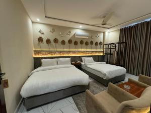 拉合尔Shelton Boulevard Hotel Lahore的酒店客房,设有两张床和一张沙发