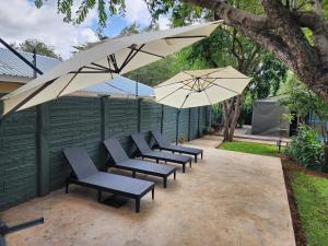 维多利亚瀑布Livingstone Lodge的庭院里摆放着一组椅子和遮阳伞