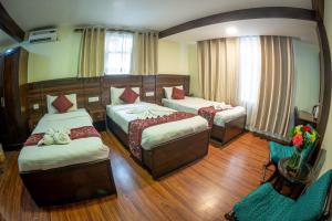 加德满都金座酒店的一间卧室配有两张床、一张沙发和一把椅子