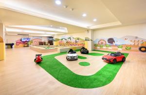 万里区群策翡翠湾温泉饭店的一间有三辆玩具车的房间,铺在绿色地毯上