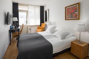 栋堡Strandhotel Domburg的一间卧室配有一张床、一张书桌和一台电视