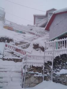 纳尔卡恩达THE WONDERLAND COTTAGES & Cafe的房屋前有雪覆盖的栅栏