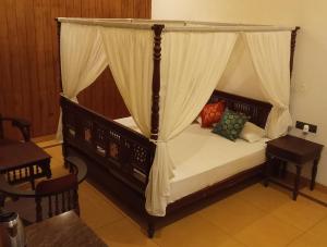 阿勒皮Shantitheeram Ayurveda Lakeside Heritage Resort的一间卧室配有一张天蓬床和一张桌子