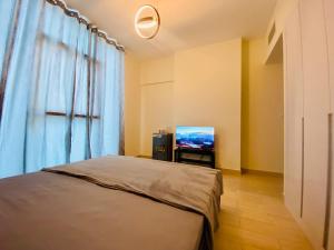 迪拜Executive Master Bedroom In Shared Apartment的一间卧室配有一张床和一台电视