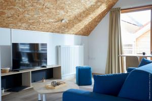 Arleux-du-NordLa Ferme Des Ailleurs的客厅配有蓝色的沙发和电视