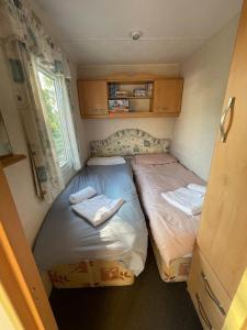 博斯2 bedroom cosy caravan的小型客房设有两张单人床和窗户。
