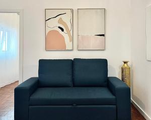 布拉干萨Cantinho do Castelo的客厅里一张蓝色的沙发,上面有绘画作品