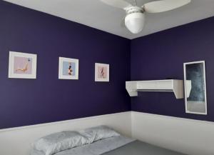 阿拉亚尔-杜卡布Serra Mar Suítes,Lofts, e casas à 300 metros das praias的卧室配有带床和风扇的紫色墙壁
