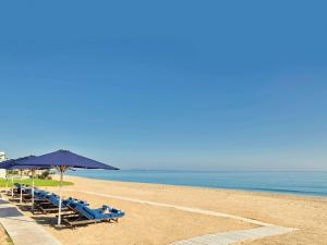 米迪克塔姆达湾海滩索菲特Spa酒店的海滩上设有蓝色的椅子和遮阳伞,还有大海