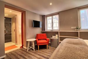 当巴克拉维尔La Grande Ourse - Chambre cosy 2 pers - L'Alcôve de l'Ours的一间卧室配有一张床、一张红色椅子和一张桌子