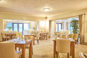 诺里奇温瑟姆山谷高尔夫乡村俱乐部酒店的餐厅设有桌椅和大窗户。