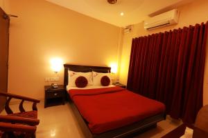 杜蒂戈林Hotel Nakshatra Inn VL Tuticorin的一间卧室配有红色的床和红色窗帘