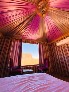 瓦迪拉姆Alora Wadi Rum Luxury的一间卧室配有一张床、两把椅子和一个窗户