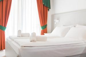 利莫内-苏尔加达加尔达贝尔维尤酒店的配有橙色窗帘的客房内的2张白色床