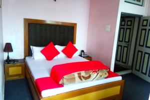 大吉岭Hotel North Point Inn Darjeeling的一间卧室配有一张带红色枕头的大床