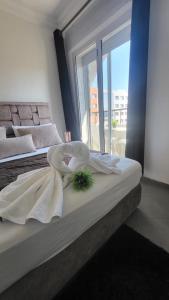 丹吉尔Appart Hotel Tanger Paname的一间卧室设有两张带白色床单的床和窗户。