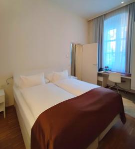 林茨阿姆多姆广场酒店 - 仅限成人入住的卧室配有一张白色大床和一张书桌