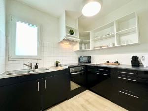 蒙德马桑LE COSY - Plain-Pied的厨房配有黑色橱柜、水槽和窗户。