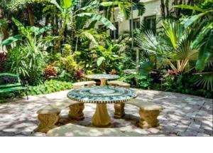 棕榈滩Romantic Studio in the Heart of Palm Beach的庭院里种有树木,设有桌子和长椅