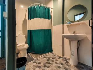 That PhanomSangthong Heritage hotel โรงแรมแสงทองเฮอริเทจ的一间带绿色淋浴帘和卫生间的浴室