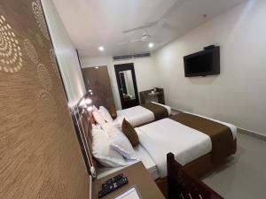 海得拉巴Hotel Landridge - HITECH City Hyderabad的酒店客房设有两张床和电视。