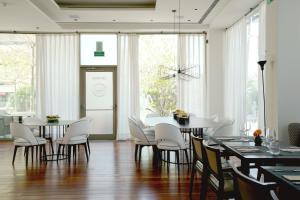 锡切斯Hotel MiM Sitges & Spa的一间设有白色椅子和桌子的用餐室以及窗户。