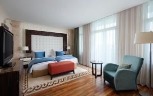 巴库Badamdar Hotel and Residences的一间卧室配有一张床、一台电视和一把椅子
