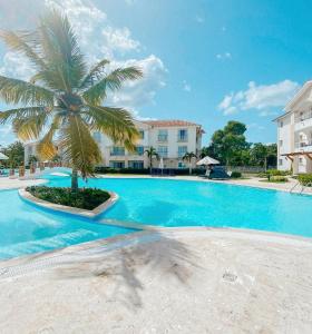 巴亚希贝Apartamento Cadaques caribe Bayahibe的一座大型游泳池,在一座建筑前方有一棵棕榈树